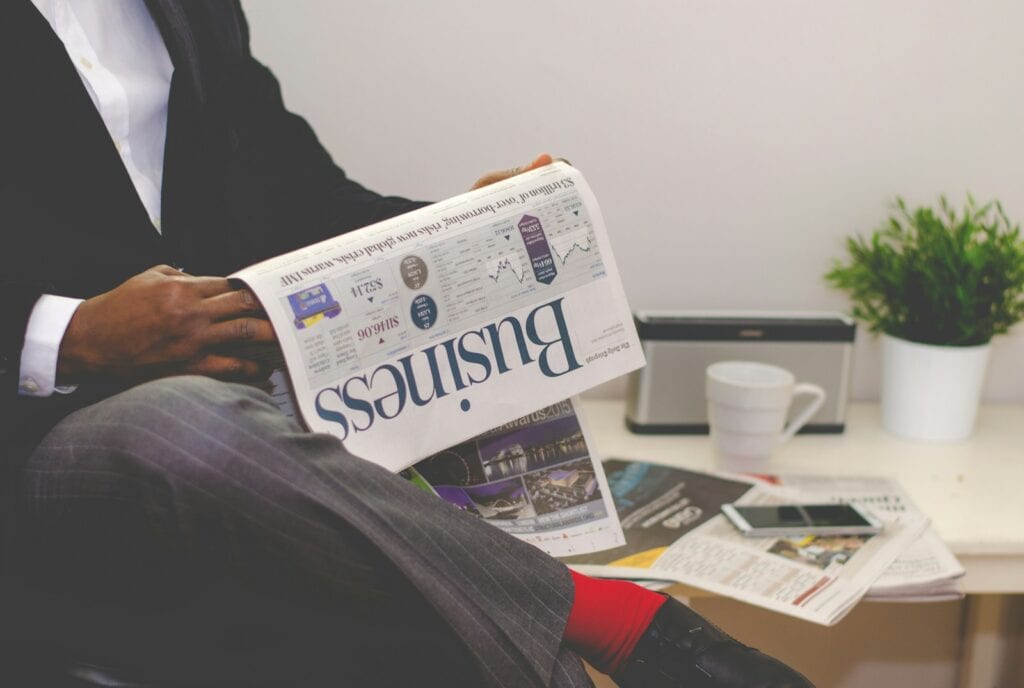 A professional reading a business newspaper in an office setting, illustrating market research and decision-making, ideal for understanding the best time to refinance mortgage rates